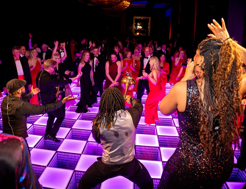Photo of crowded dance floor with band playing.